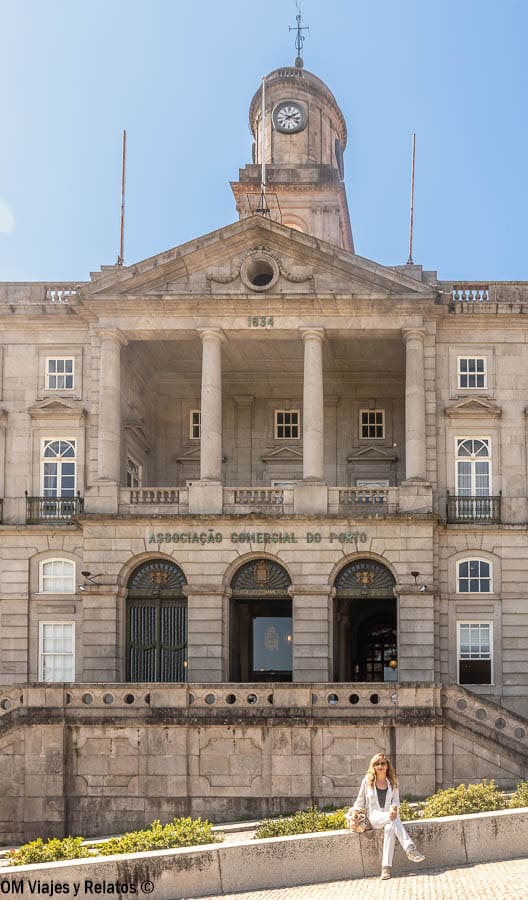 Servidora posando frente al Palácio da Bolsa (Asociación Comercial de Oporto) con fachada clásica y torre con reloj, un lugar histórico que ver en Oporto en 2 días.