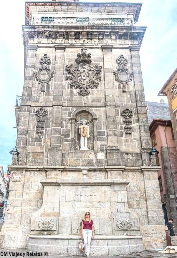 Servidora posando frente a la Fonte da Praça da Ribeira, fuente histórica de piedra en el centro de Oporto, un rincón con encanto que ver en Oporto en 2 días.