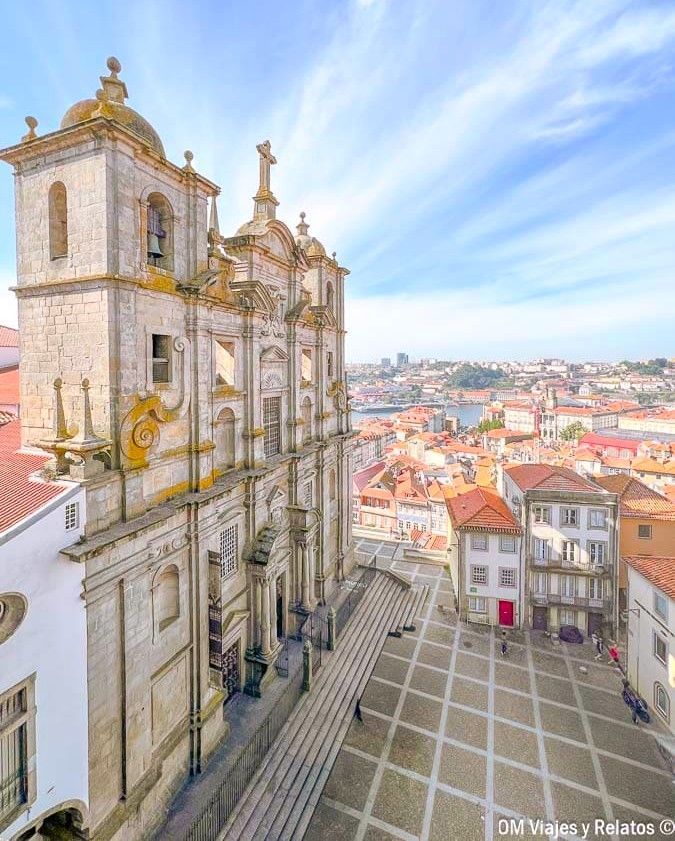 Fachada de una iglesia barroca con escalinata y vistas al casco histórico de tejados rojos de Oporto y al río Duero, uno de los miradores imprescindibles que ver en Oporto en 2 días.