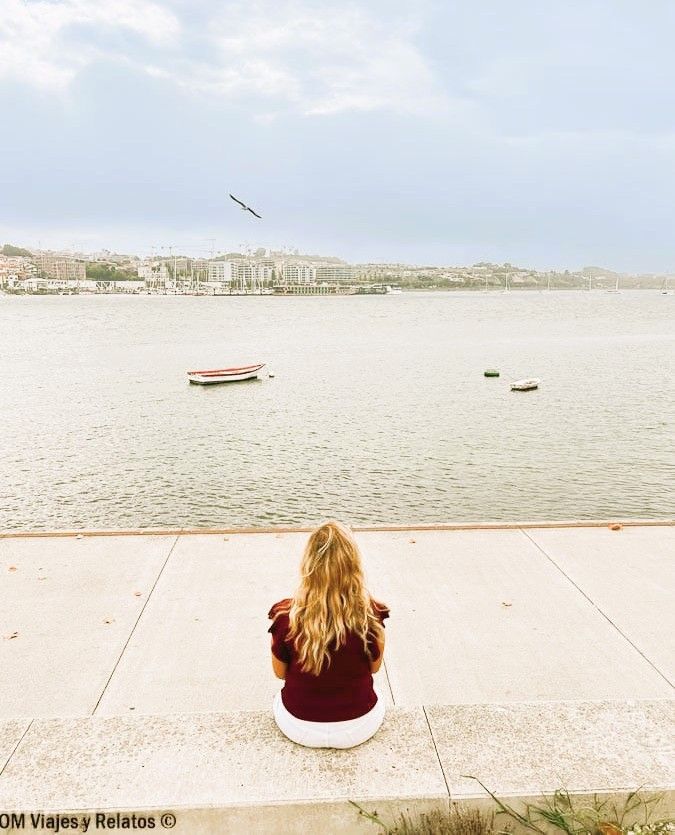 Servidora sentada de espaldas frente al río Duero en Oporto, con barcas y gaviota al fondo, un plan tranquilo que ver en Oporto en 2 días.