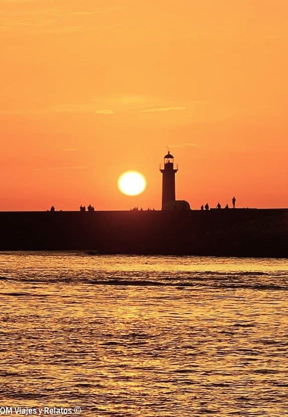 Atardecer en el faro de Foz do Douro en Oporto, cielo naranja sobre el Atlántico y siluetas de personas en el espigón – que ver en Oporto en 2 días.