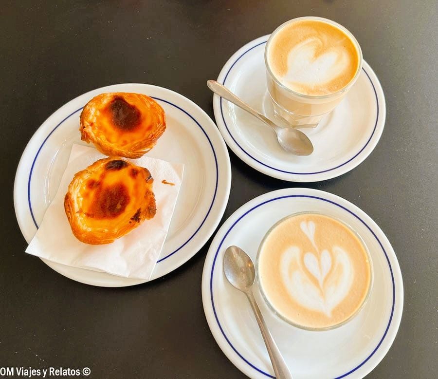 Pastéis de nata con dos cafés con latte art en una cafetería de Oporto, una parada deliciosa que ver en Oporto en 2 días.
