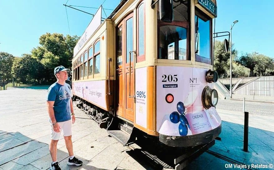 JC junto a un tranvía histórico de Oporto en una parada, una experiencia clásica de transporte que ver en Oporto en 2 días.
