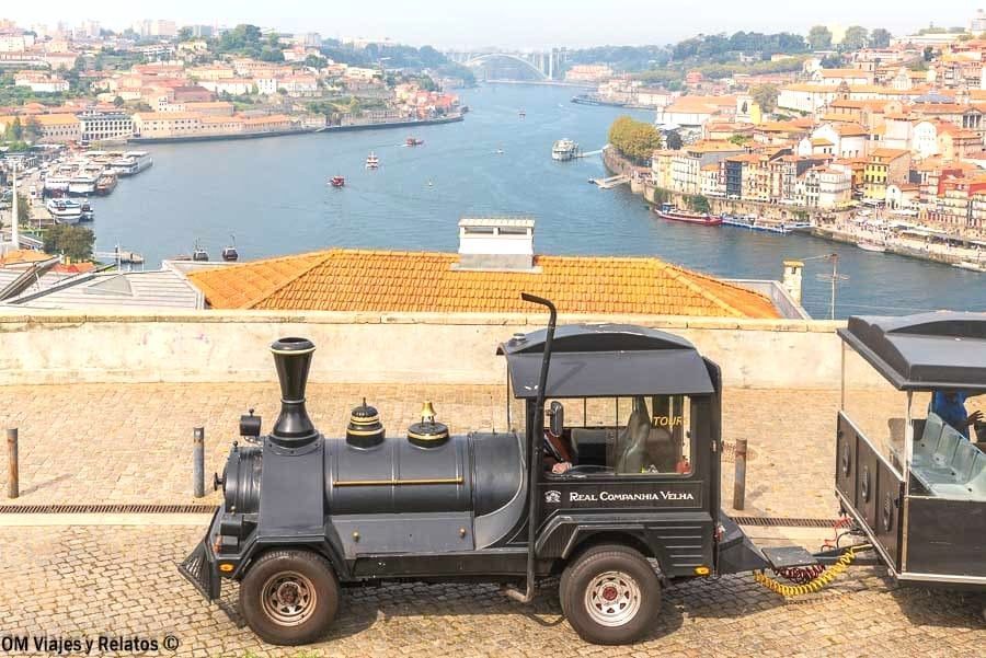 Tren turístico en un mirador de Vila Nova de Gaia con vistas al río Duero y el barrio de Ribeira, una panorámica imprescindible que ver en Oporto en 2 días.