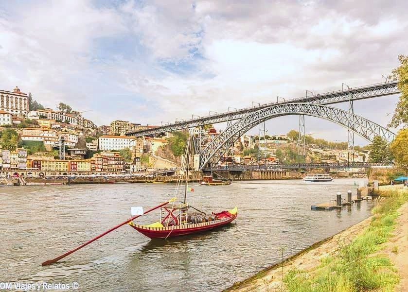 Barco rabelo navegando por el río Duero con el Puente Don Luis I al fondo, una postal imprescindible que ver en Oporto en 2 días.