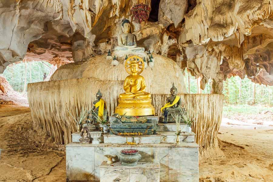 Altar con Budas dorados y figuras en cueva del Templo del tigre Tailandia