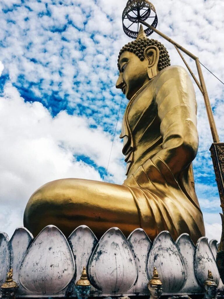 Primer plano del gran Buda dorado del Templo del tigre Tailandia bajo cielo nublado.