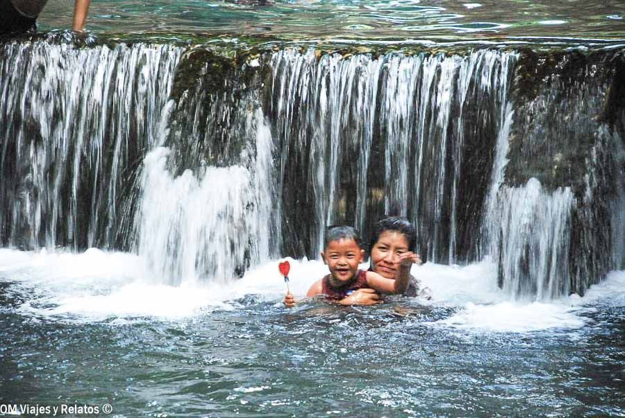 Madre e hijo bañándose bajo una pequeña cascada en excursión cerca del Templo del tigre Tailandia.