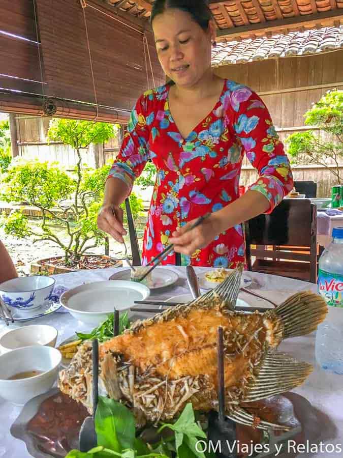 Delta del Mekong Vietnam: comida típica con pescado frito entero servido en mesa, preparado por una cocinera local.