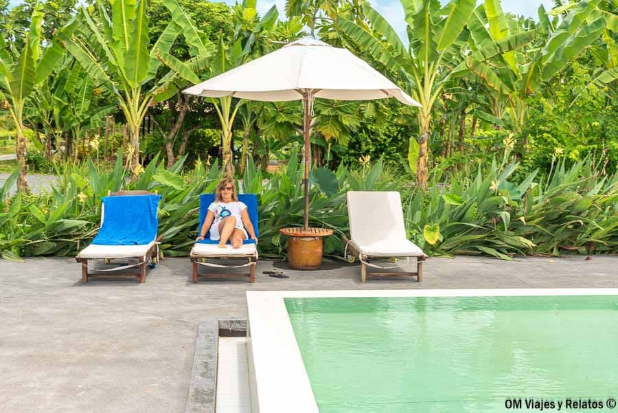 Una servidora relajándose en una tumbona junto a la piscina del alojamiento en el Delta del Mekong, Vietnam, rodeada de vegetación tropical y plataneras