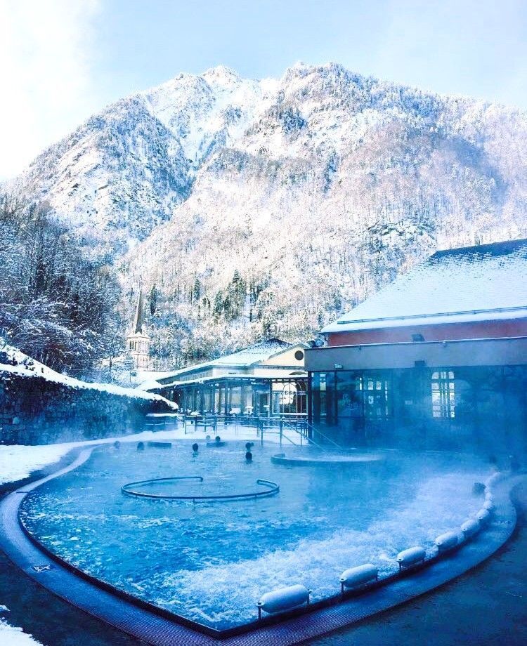 Piscina termal al aire libre del balneario Le Bains du Rocher con vapor y montañas nevadas alrededor, una escapada perfecta desde los pueblos más bonitos del Pirineo Francés.