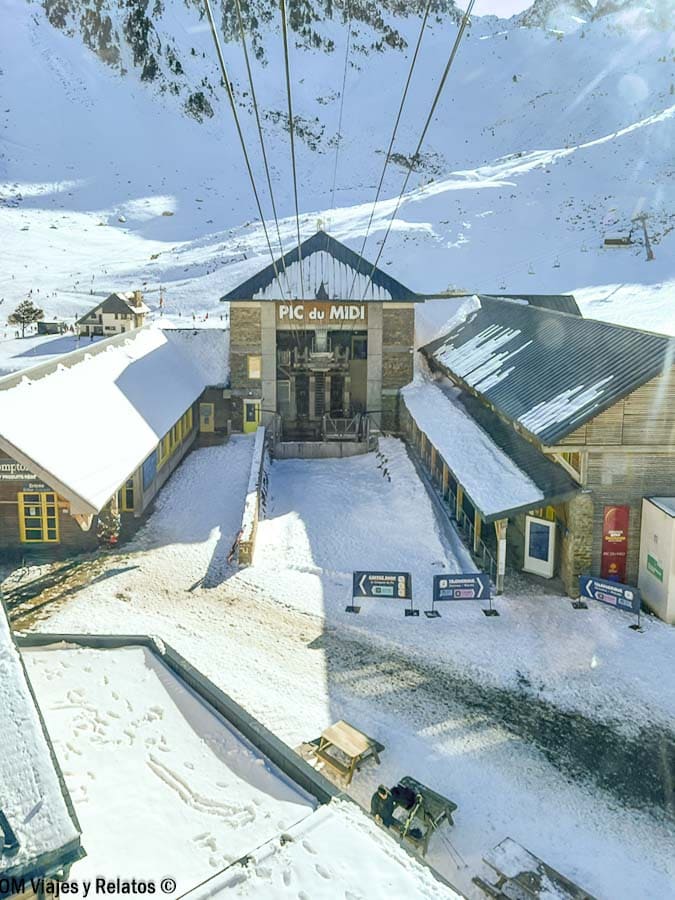 Vista desde el teleférico subiendo a la cumbre del Pic du Midi con la estación nevada y los cables en primer plano, una aventura cerca de los pueblos más bonitos del Pirineo Francés.