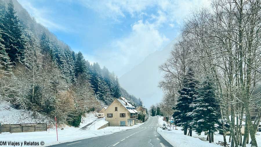 Carretera nevada entre bosques y casas de montaña de camino a Hautes-Pyrénées, una ruta escénica hacia los pueblos más bonitos del Pirineo Francés.