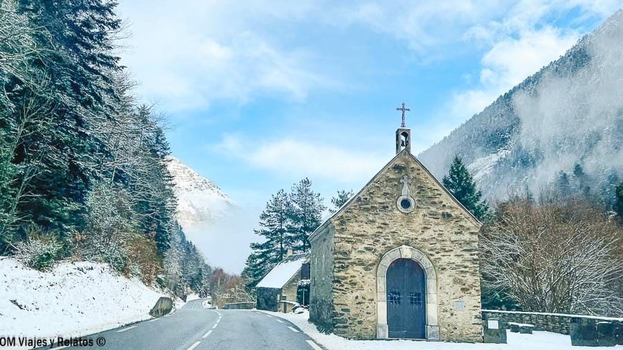 Pequeña iglesia de piedra junto a una carretera nevada en un valle del Pirineo, un rincón con encanto rumbo a los pueblos más bonitos del Pirineo Francés.