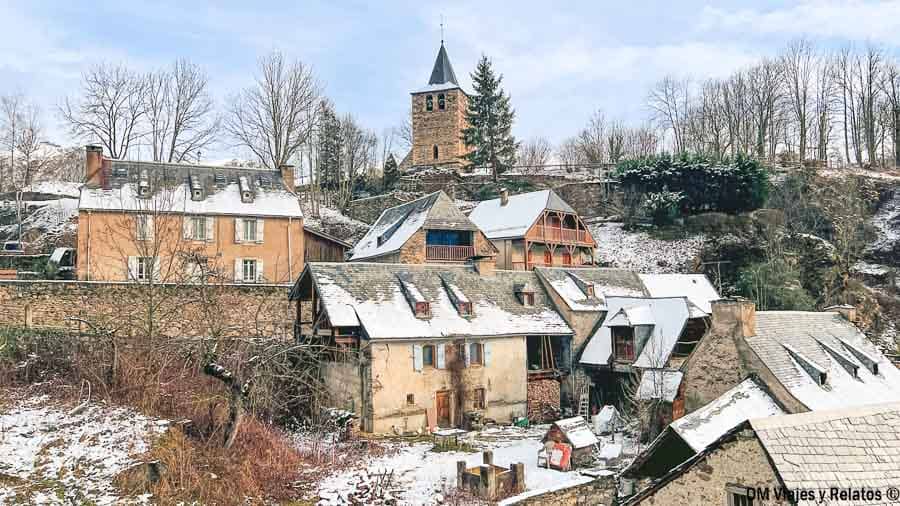 Casas de piedra con tejados nevados y una iglesia con campanario en un pueblo del Pirineo, uno de los pueblos más bonitos del Pirineo Francés.