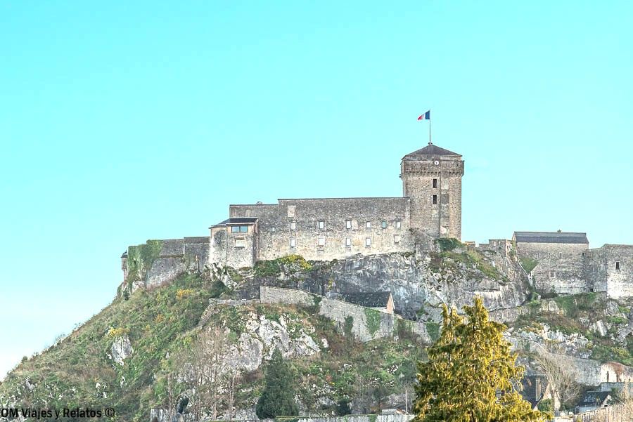 Vista del castillo fortificado de Lourdes desde la basílica, sobre una colina con bandera de Francia, en la ruta por los pueblos más bonitos del Pirineo Francés.