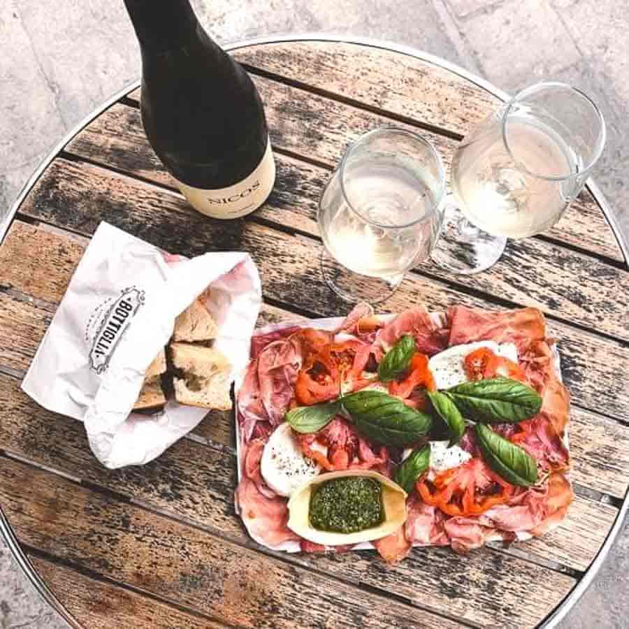 Tabla de embutidos italianos con vino blanco en una terraza típica de Venecia, una experiencia gastronómica imprescindible que ver en Venecia en 3 días.