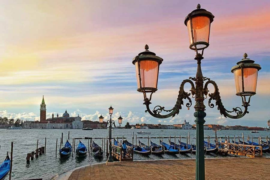 Que ver en Venecia en 3 días: góndolas amarradas al atardecer frente a San Giorgio Maggiore y farolas en primer plano.