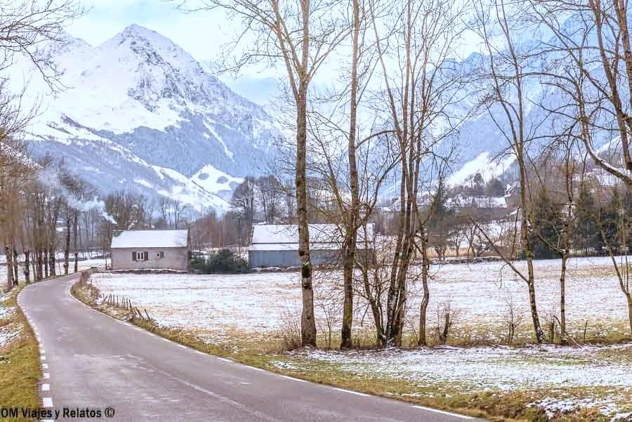 Carretera rural entre campos nevados y montañas del Pirineo Francés, un paisaje de ruta hacia los pueblos más bonitos del Pirineo Francés.