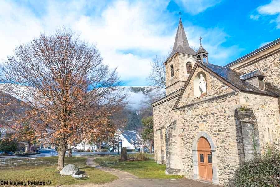 Fachada de piedra de la Chapelle Sainte-Marie de Saint-Lary en Saint-Lary-Soulan, con campanario y montaña al fondo, una parada con encanto en los pueblos más bonitos del Pirineo Francés.