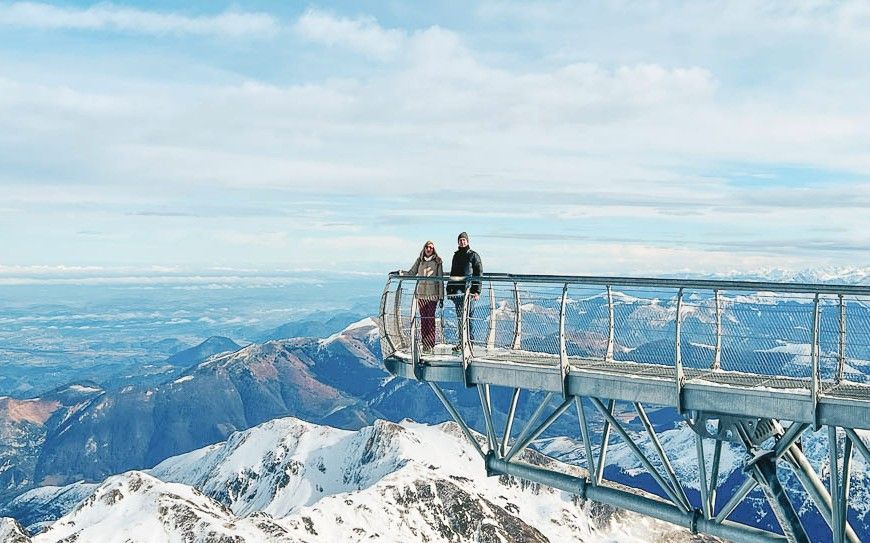 Mirador del Pic du Midi (pontón del cielo) una servidora y JC sobre una pasarela suspendida y vistas a cumbres nevadas, una escapada cerca de los pueblos más bonitos del Pirineo Francés.
