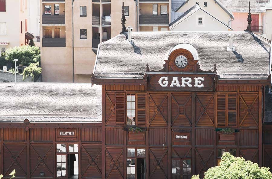 Fachada de madera de la antigua estación “Gare” en Cauterets, con reloj y cartel de billetes, un rincón con encanto en la ruta por los pueblos más bonitos del Pirineo Francés.