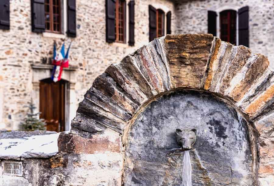 Fuente de piedra con caño en forma de animal y arco rústico en Saint-Lary-Soulan, un detalle con encanto de los pueblos más bonitos del Pirineo Francés.