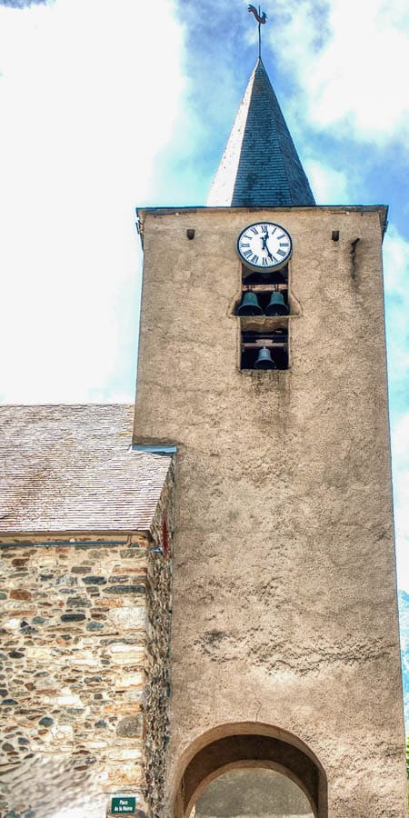 Campanario de la iglesia de Loudenvielle con reloj en la torre, una parada con encanto en los pueblos más bonitos del Pirineo Francés.