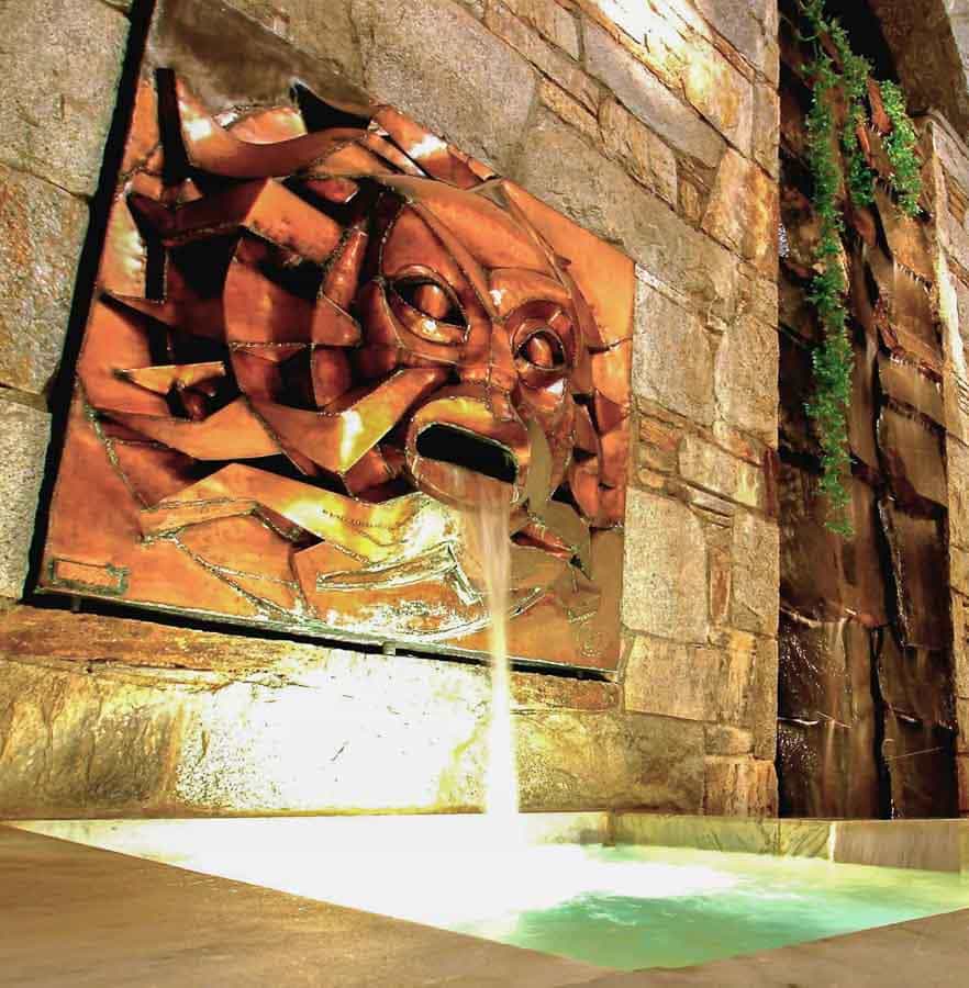 Fuente ornamental con máscara de cobre vertiendo agua en el balneario Sensoria-Spa, una experiencia de relax cerca de los pueblos más bonitos del Pirineo Francés.