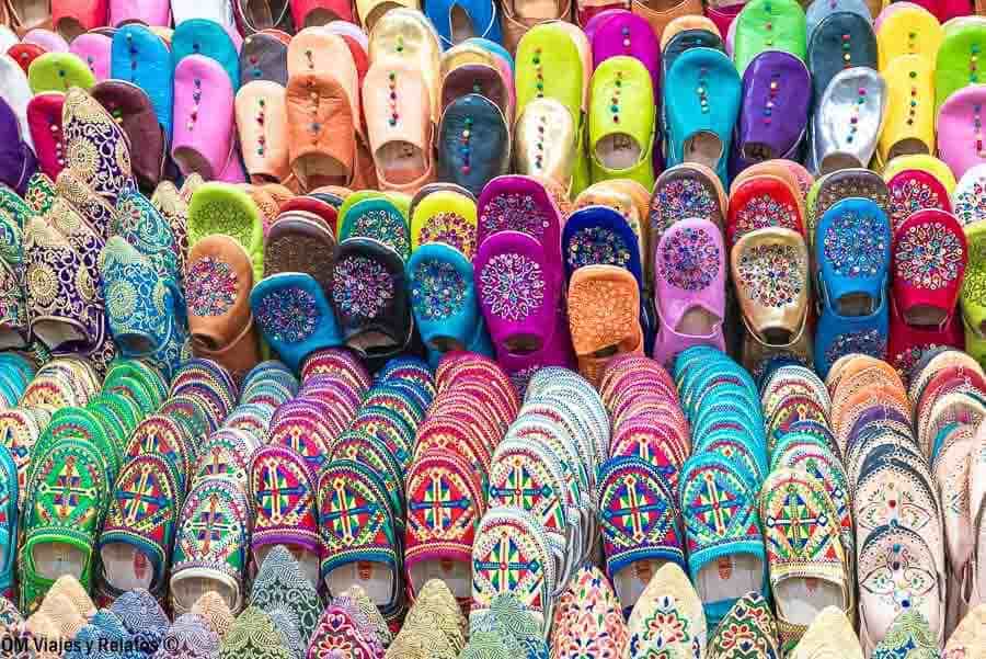 Babuchas marroquíes de colores en un puesto del zoco, imprescindible en la lista de qué ver en Marrakech en 4 días.