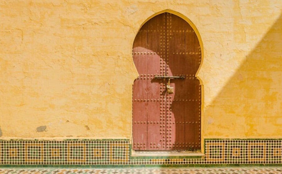 Puerta marroquí con arco y azulejos tradicionales, ideal para consejos para viajar a Marruecos y visitar medinas.