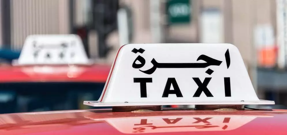 Cartel de taxi en árabe y en inglés, útil para consejos para viajar a Marruecos sobre transporte y precios.