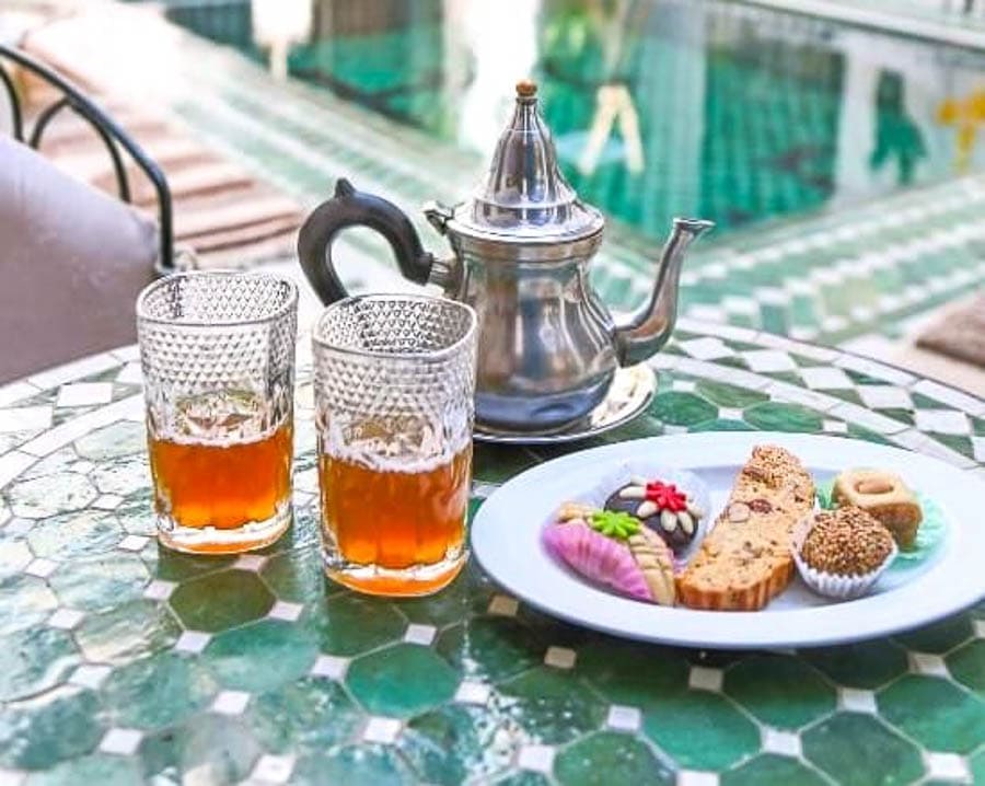 Té moruno y dulces marroquíes servidos en una mesa de mosaico, un clásico en consejos para viajar a Marruecos.