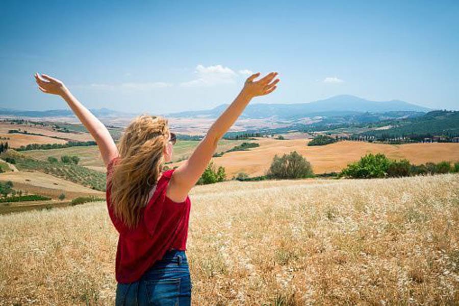 Servidora disfrutando del paisaje de la Toscana en un campo abierto, una idea top para excursiones desde Roma de un día.