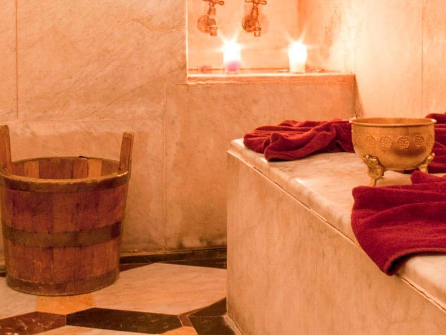 Interior de un hammam en Marrakech con velas, toallas y cubo tradicional, plan relajante de qué ver en Marrakech en 4 días.