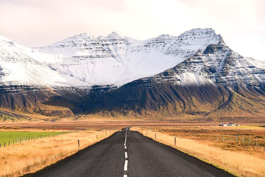 Carretera en Islandia con montañas nevadas al fondo y paisaje otoñal, perfecta para un viaje a Islandia en octubre.