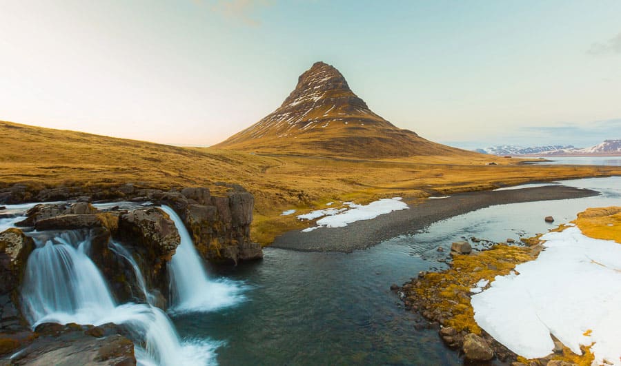 Montaña Kirkjufell con la cascada Kirkjufellsfoss y nieve alrededor, un paisaje imprescindible en Islandia en octubre.