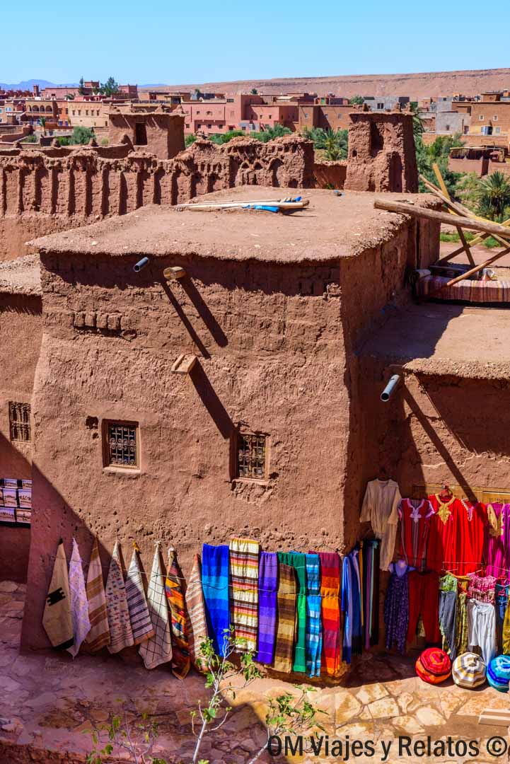 Puestos de alfombras y telas de colores en una kasbah de adobe, parada local en una ruta por Marruecos en coche.
