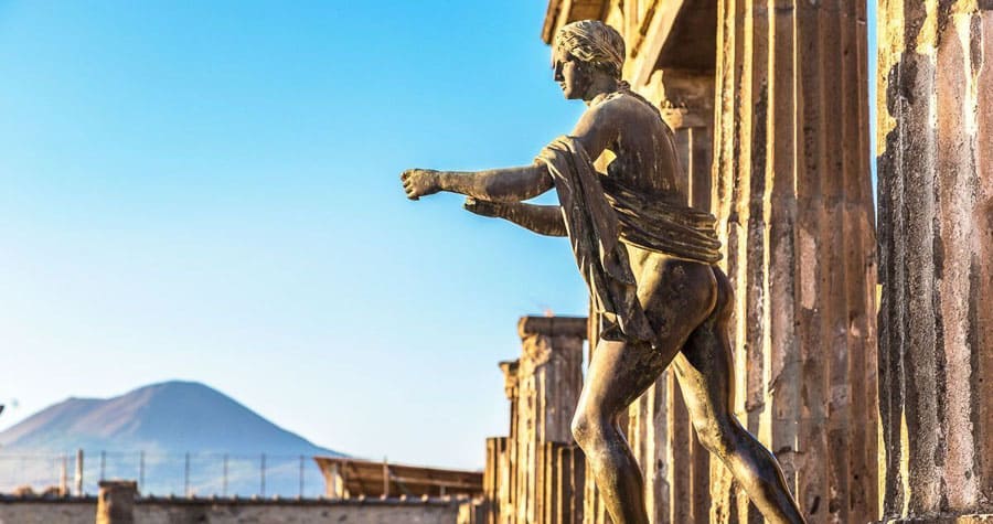 Estatua en las ruinas de Pompeya con el Vesubio al fondo, un plan imprescindible de que ver cerca de Roma en un día.