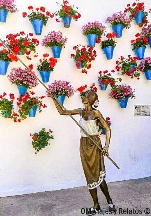 Mural de los patios cordobeses con macetas azules y flores en una pared blanca, imprescindible en que ver en Córdoba en un día.