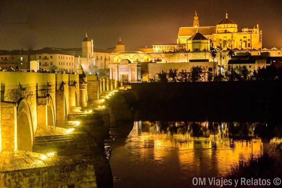 Puente Romano de Córdoba iluminado de noche con la Mezquita-Catedral al fondo, imprescindible en que ver en Cordoba en un día.