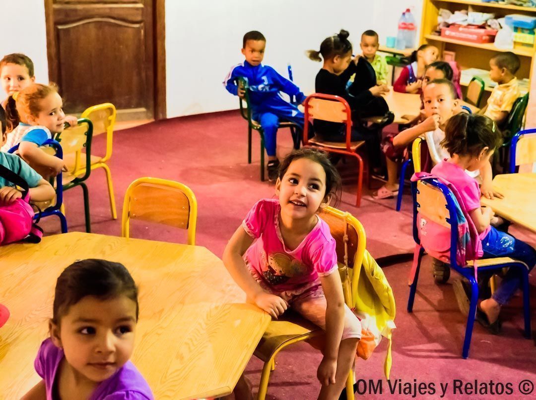 Niños sentados en un aula de guardería con mesas y sillas de colores, durante una visita en Marruecos.