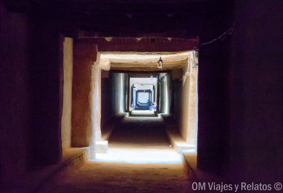Pasillo interior de una kasbah con arcos y luz al fondo, escena única en una ruta por Marruecos en coche.