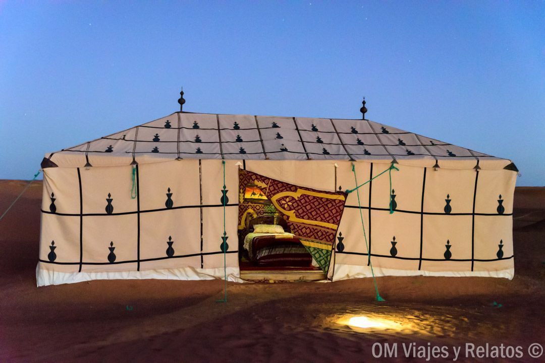 Jaima bereber iluminada en el desierto al anochecer, noche inolvidable en una ruta por Marruecos en coche.