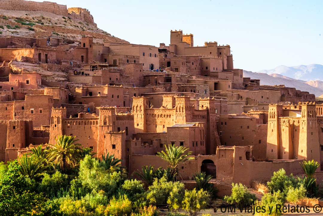 Kasbah tradicional de adobe entre palmeras al atardecer, parada imprescindible en una ruta por Marruecos en coche.