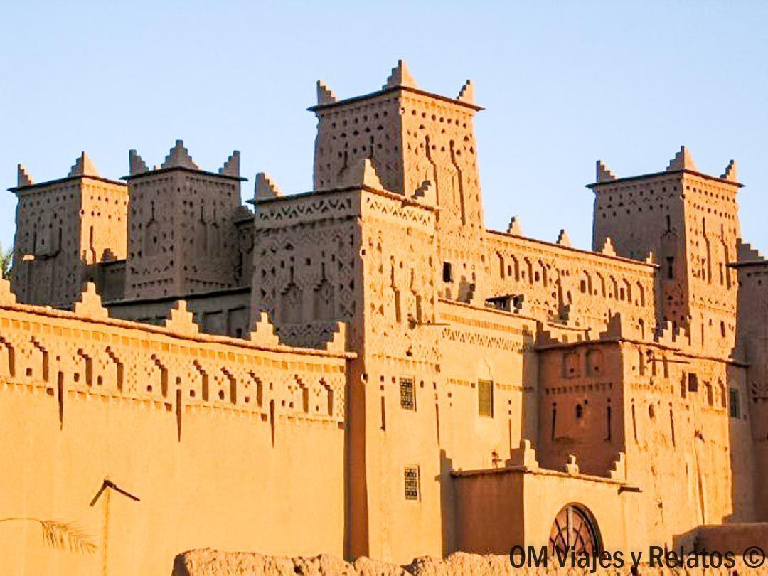Kasbah de adobe con torres y murallas al atardecer, una visita típica en rutas en coche por Marruecos.