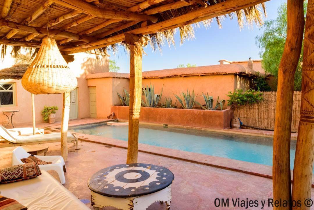 Patio de un riad con piscina y zona de sombra, un alojamiento ideal en rutas en coche por Marruecos.