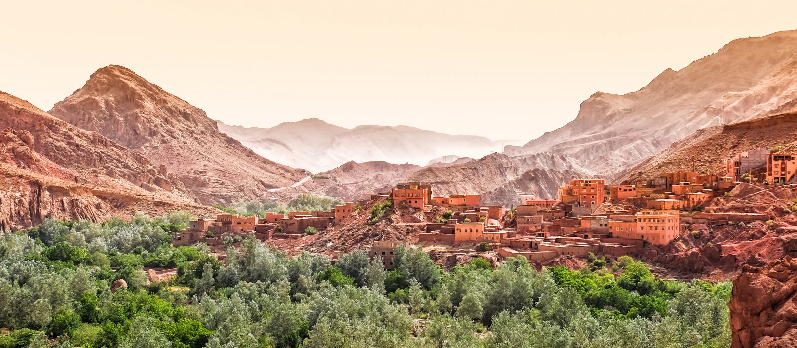 Panorámica de un pueblo bereber entre montañas y valle verde, paisaje imprescindible en una ruta por Marruecos en coche.