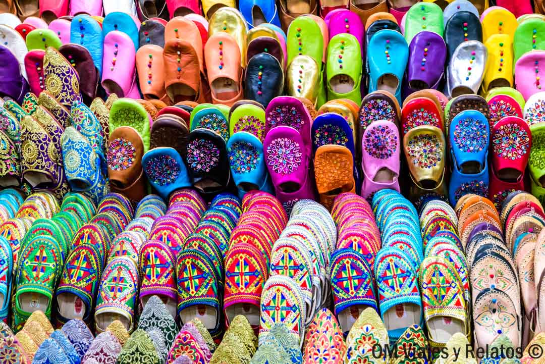 Babuchas marroquíes de colores en un zoco tradicional, compras típicas en una ruta por Marruecos en coche.
