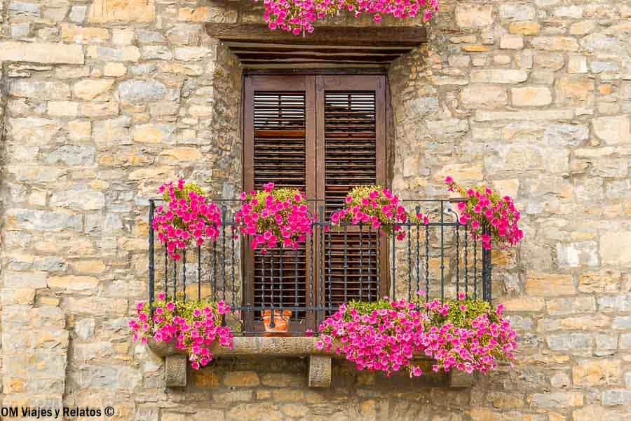 Balcón con flores en una casa de piedra en Aínsa, una parada con encanto de que ver en Ordesa y Monte Perdido.